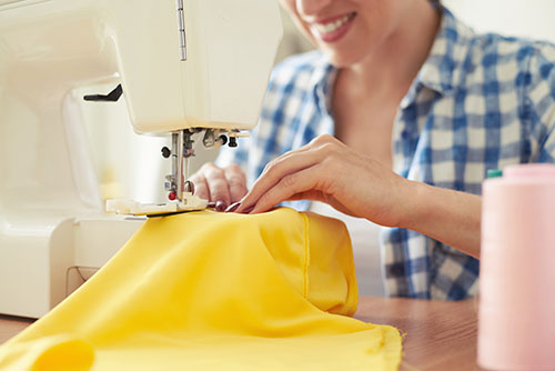 smiley woman sewing on sewing-machine. focus on sewing-machine
